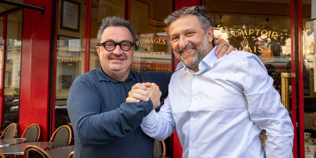 Deux restaurateurs se serrent la main devant un établissement