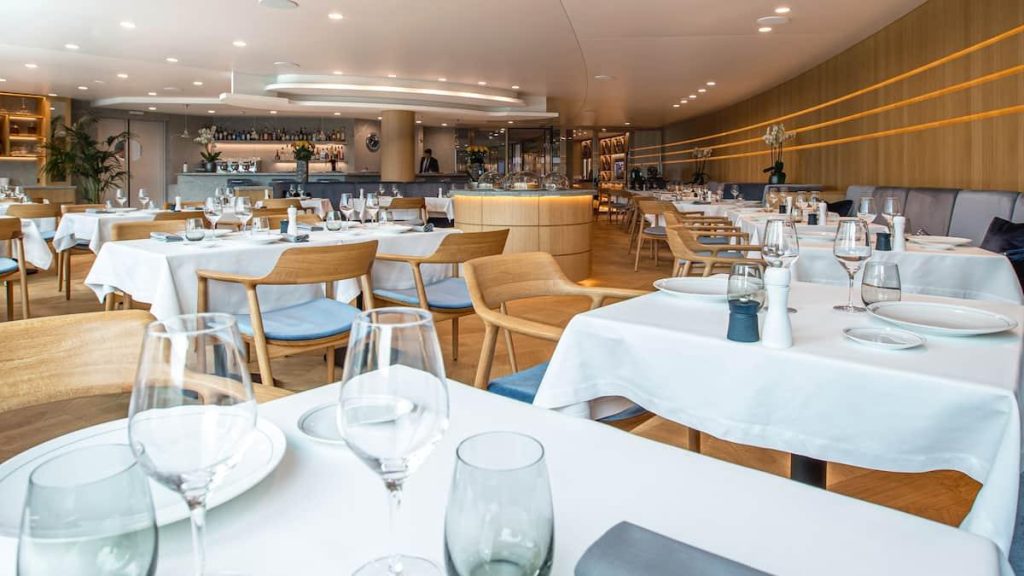 Salle de restaurant dressée, tables nappées de blanc